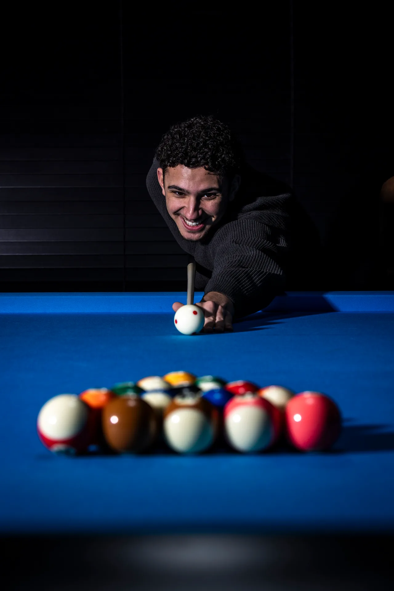 Man richt op de witte bal op een pooltafel met een aanslagstok bij Oscars Bowling & Pool